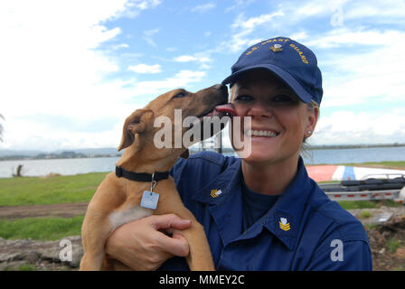 Petty Officer 1st Class Jana James spielt mit ihrem Neu Hund gerettet, Soldat, auf dem Rasen von San Juan, Puerto Rico, Okt. 28, 2018. James, ein reservist mit Marine Safety Unit Savannah, GA., bereitgestellt von San Juan für 60 Tage zur Unterstützung der Hurrikan Maria Antwort. U.S. Coast Guard Foto von Petty Officer 2. Klasse Matthew Masaschi. Stockfoto