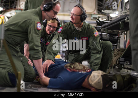 Staff Sgt. Avery Keller (vorne), zweite aeromedical evacuation Techniker, Staff Sgt. Sarah Bell (Mitte), Medizintechnik und Maj. Jeff Gerste (rechts), medizinische Crew Director, alle aus der 137 Aeromedical Evacuation Squadron, Will Rogers Air National Guard Base, Oklahoma City, einem simulierten Patienten zurückzuhalten, Senior Airman Andrew Dyer, 137 Special Operations Logistik Bereitschaft Geschwader von der gleichen Basis, wie er sich eine Flucht Szenario während der Transport an Bord eines C-17 Globemaster III von der 105 Airlift Wing, Stewart Air National Guard Base, N.Y., en Route zu Altu Stockfoto