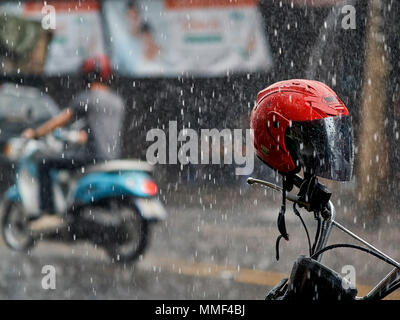 Motorrad Regen fahren. Motorrad bei sintflutartigen Niederschlägen. Monsun-Saison in Thailand. Südostasien. Motorradhelm rot Stockfoto