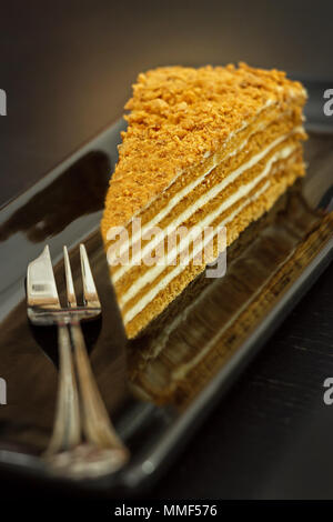 Ein Stück der traditionelle Honig Kuchen auf einer schwarzen Platte. Der dunkle Hintergrund. Geringe Tiefenschärfe. Selektive konzentrieren. Stockfoto