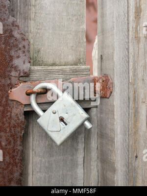 Alte hölzerne Tor mit einem Vorhängeschloss auf der Schraube. Stockfoto