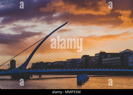 DUBLIN, Irland - Mai 9., 2018: Majestic orange und rosa getönten Sonnenuntergang über dem Fluss Liffey in Dublin, mit der Samuel Beckett Brücke Stockfoto