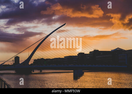 DUBLIN, Irland - Mai 9., 2018: Majestic orange und rosa getönten Sonnenuntergang über dem Fluss Liffey in Dublin, mit der Samuel Beckett Brücke Stockfoto