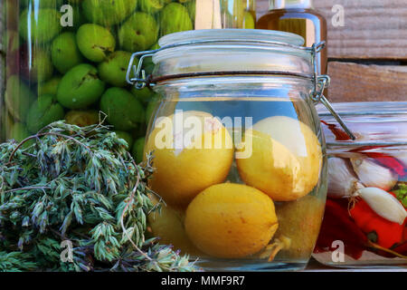 Fermentiertes Gemüse in Gläsern. Vegetarisches Essen Konzept. Zitronen, Oliven, Paprika, Chilis, Olivenöl, Oregano Stockfoto