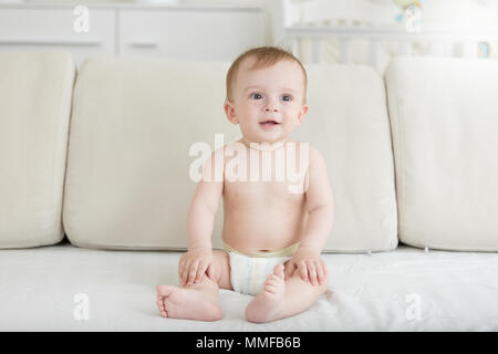 Portriat von adorable 10 Monate alt baaby Junge in Windeln sitzen auf einem Sofa Stockfoto