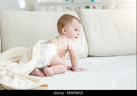 Adorable 10 Monate alten Baby boy in Windeln sitzen auf einem Sofa Stockfoto