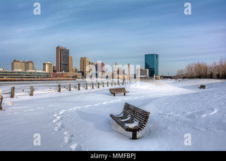 Ein Blick auf die Innenstadt von Toledo Ohio Skyline aus über die gefrorene und schneebedeckten Maumee River eine schöne leicht bewölkt blauer Himmel. Stockfoto