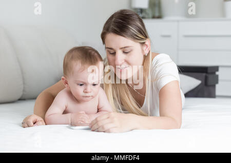 Portrait von adorable Baby Boy liegend auf Bett mit Mutter und sich Zeichentrickfilme auf Tablet-PC Stockfoto