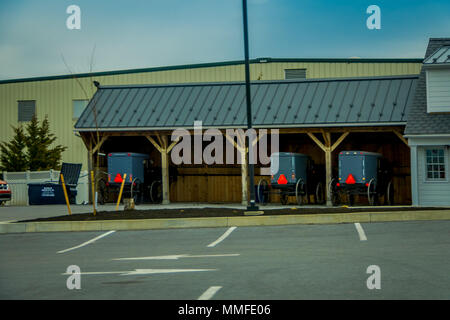 Pennsylvania, USA, April, 18, 2018: herrlich freien Blick auf unscharfen Amish Buggies unter einer Holzkonstruktion in Lancaster County Farm bei einem bewölkten Tag geparkt Stockfoto