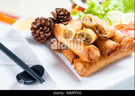 Knusprig gebratene Frühlingsrollen mit Pflaumen Soße und Salat, Zitronenscheiben auf hölzernen Tisch Stockfoto