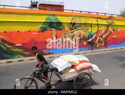 New Delhi, Indien. 11. Mai, 2018. Ein Mann reitet auf einem Wagen vor einem großen Graffiti der hinduistischen Gott, Herr Hanuman, auf eine Überführung Brücke in der Nähe von Hanuman Tempel in Neu Delhi, Indien, 11. Mai 2018. Credit: Stinger/Xinhua/Alamy leben Nachrichten Stockfoto