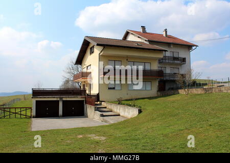 Zwei angeschlossene Suburban family Häuser auf kleinen Hügel mit hölzernen Zaun Balkone und Garagen mit frisch geschnittenem Gras auf Wolke umgeben Stockfoto