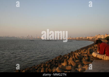 Indische Mann sitzt am Meer am Marine Drive, Mumbai, Indien Stockfoto