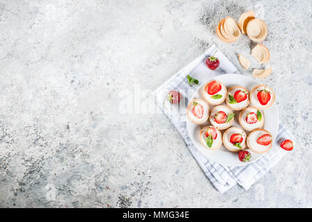 Sommer süße hausgemachte Desserts, Mini Käsekuchen mit Erdbeeren auf grauem Stein Tabelle kopieren Raum, Ansicht von oben Stockfoto