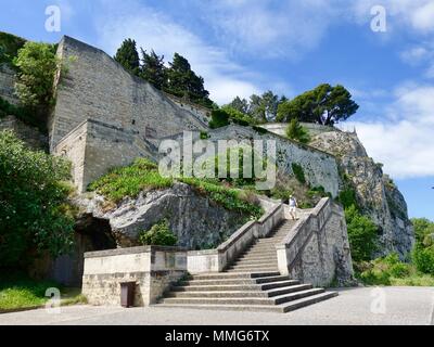 Mann mit Rucksack und Shorts steigt die steilen Stufen von der Rocher des Doms Gärten vor den Stadtmauern von Avignon, Frankreich Stockfoto