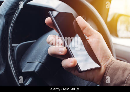 Man Autofahren und mit Handy für Sms, gefährlich und rücksichtslos Verhalten im Verkehr, die Unfälle verursacht. Stockfoto
