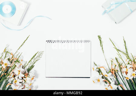 Blick von oben auf die leere notepad unter rustikale Sommer Blumen und Geschenkboxen auf weißem Hintergrund. Florale flach symmetrische Komposition mit leeren Blatt auf Stockfoto