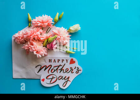 Festliche Komposition mit Text der glückliche Mutter Tag auf Candy blauer Hintergrund. Blumen in Hülle. Grußkarte mit Spring Bouquet. Stockfoto
