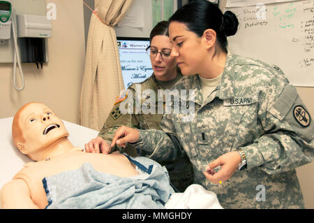 Maj. Maria Pescatore, Clinical Nurse Specialist, Medical & Surgical Ward, William Beaumont Army Medical Center, beauftragt 2. Lt. Lizamara Bedolla, Stationsschwester, Chirurgische Abteilung, WBAMC, die auf einer angemessenen Verfahren für eine peripher Eingefügt zentralvenösen Katheter (PICC) Linie Verbandwechsel mit hoher Wiedergabetreue normpuppe an Wbamc der Zentralen Simulation Ausschuss medizinische Simulation Center, der 4. Oktober 2017. Die medizinische Simulation Center der WBAMC wurde vor kurzem die vorläufige Zulassung der Gesellschaft für Simulation in Healthcare, eine internationale medizinische Simulation beglaubigenden Organisation gewährt. Stockfoto