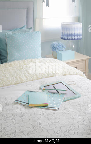 Blaue Farbe Notebook auf dem Bett in hellen Blautönen Schlafzimmer Innenraum Stockfoto