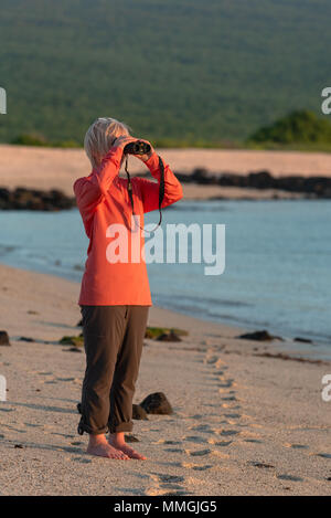 Frau Suchen durch ein Fernglas auf einem Strand auf den Galapagosinseln, Ecuador. Stockfoto