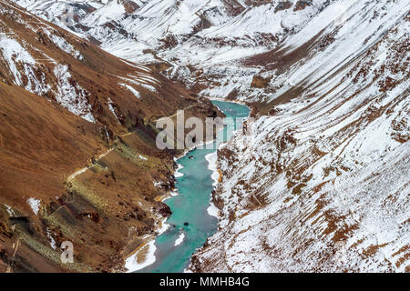 Indus River fließt durch den Schnee in den Bergen des Himalaya (Ladakh Range) auf der einen Seite und auf der anderen Seite mit einer kargen Berg bedeckte. Stockfoto