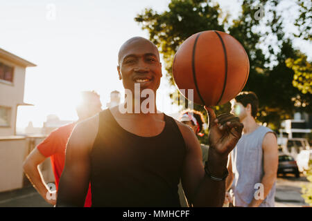 Vier basketball Männer auf der Straße nach einem Spiel der Basketball. Man spinnen Basketball auf seinen Daumen. Stockfoto