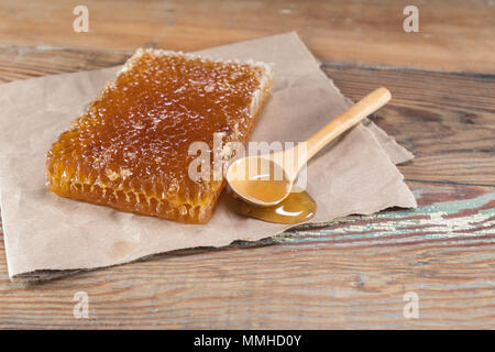 Honey Comb und verschüttete Honig auf Holzbrett Stockfoto