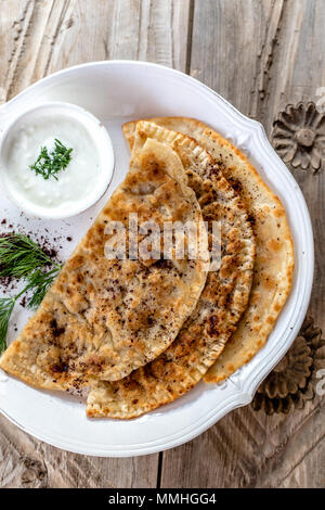 Traditionelle aserbaidschanische Küche. Obere Ansicht geschossen von qutabs - fladenbrot auf weißer Keramik Teller. Vertikale Komposition. Stockfoto