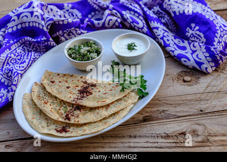 Traditionelle aserbaidschanische Küche. Qutabs Fladenbrot mit Grüns auf weißer Keramik Platte über der hölzernen Tischplatte. Horizontale Komposition. Stockfoto