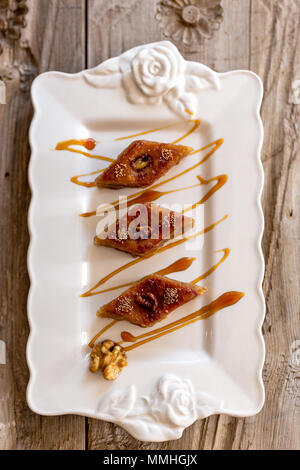 Obere Ansicht geschossen von traditionellen aserbaidschanischen Baklava mit Nussbaum in Ceramic White Platte über rustikal Tischplatte. Vertikale Komposition. Stockfoto