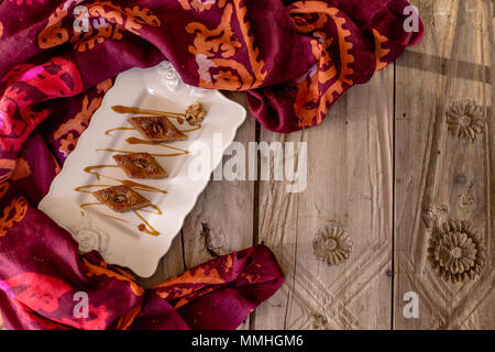 Obere Ansicht geschossen von traditionellen aserbaidschanischen Baklava mit Nussbaum in Ceramic White Platte über rustikal Tischplatte. Horizontale Komposition. Platz kopieren Stockfoto