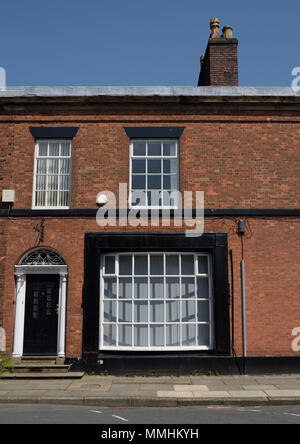 Zweistöckiges Reihenhaus aus rotem Backstein mit weißem Holzfensterrahmen und schwarzer Umrandung, schwarze Tür mit weißer Ziertürumrandung in Bury uk Stockfoto