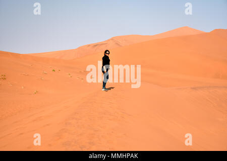 Frau geht auf die roten Dünen der Namib Wüste Namib Naukluft National Park, Sossusvlei, Sesriem, Namibia Stockfoto