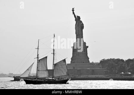 Ein altes Segelboot Segel vor der Freiheitsstatue am Eingang auf den Hafen von New York, New York, USA Stockfoto