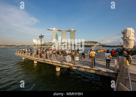 Touristen, die am Abend in Singapur den Halbfisch und den Halblion des berühmten Merlion auschecken. Stockfoto