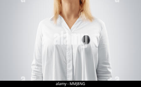 Leeren schwarzen Anstecker mockup auf der womans Brust festgesteckt, bis Anzeigen schließen. Mädchen trägt ein weißes Hemd und grau Kampagne pin Mock up. Freiwillige runde Emblem design Element. Person mit Stimmrecht, Symbol Stockfoto