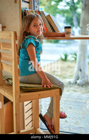 Kleines Mädchen trinken Kaffee am Tisch Stockfoto