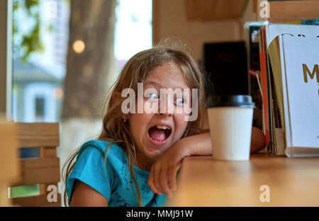 Kleines Mädchen trinken Kaffee am Tisch Stockfoto