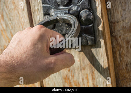 Männliche Hand öffnen alte Holztür mit sehr alten Türgriff. Close Up, selektiver Fokus Stockfoto