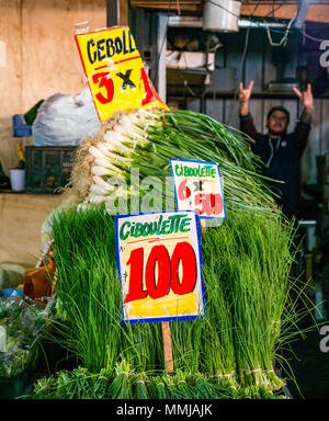 Frühlingszwiebeln zum Verkauf mit Markt Verkäufer im Hintergrund geben V Sign, Patronata Obst- und Gemüsemarkt, Santiago, Chile, Südamerika Stockfoto