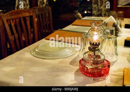 Öllampe, Gläser und Teller auf einem Tisch in einer traditionellen griechischen Taverne in Skiathos, Griechenland. Stockfoto