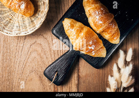 Frisch gebackene Croissants bestreut mit Puderzucker auf Tisch Stockfoto