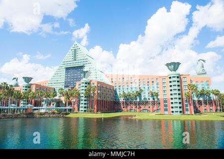 Blick auf die Deluxe Dolphin Hotel, vom Epcot gesehen-zu-Dolphin-Hotel Boardwalk. Sonnigen blauen Himmel. Flauschigen weißen Wolken. Bunte Wasser Reflexion. Stockfoto