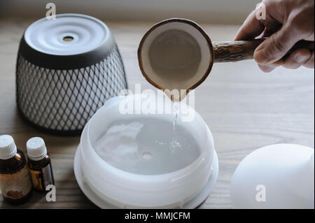 Ein Mann gießt Wasser in den Aroma-Diffusor. Stockfoto