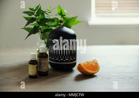 Die ultraschall Aroma-diffusor ist im orientalischen Stil. Es gibt aromatische Öle und eine Scheibe Orange in der Nähe der Diffusor auf dem Tisch. Stockfoto