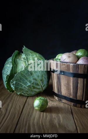 Auswahl an frischen Garten Gemüse (Weißkohl, Rosenkohl und rosa Kartoffelknollen) auf natürlichen Holz- Hintergrund. Selektive konzentrieren. Rustikale st Stockfoto