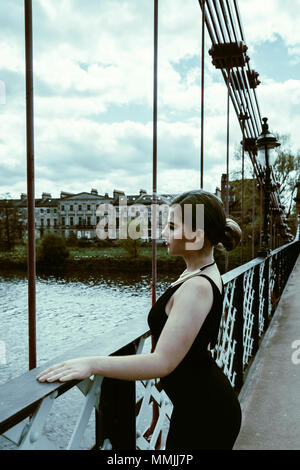 Seitenansicht des schönen Frau auf einer Brücke mit schwarzen Kleid Stockfoto