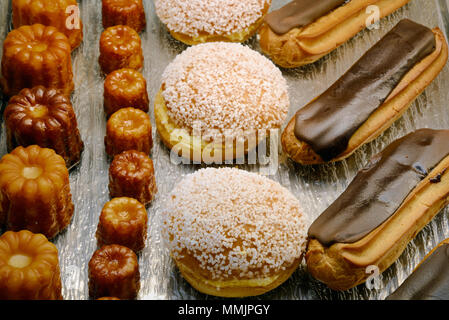 Anzeige von Tropezienne Canelés, Kuchen & Chocolate Eclairs Kuchen und Gebäck in einem französischen Patisserie Frankreich Stockfoto