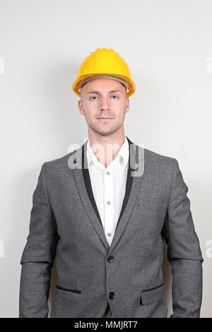 Junge Unternehmer im grauen Anzug mit gelben Schutzhelm Stockfoto